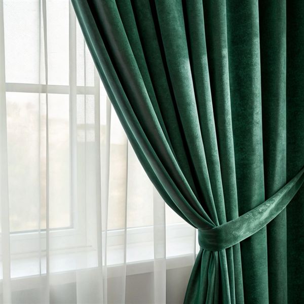 Green velvet curtain tied back at a window